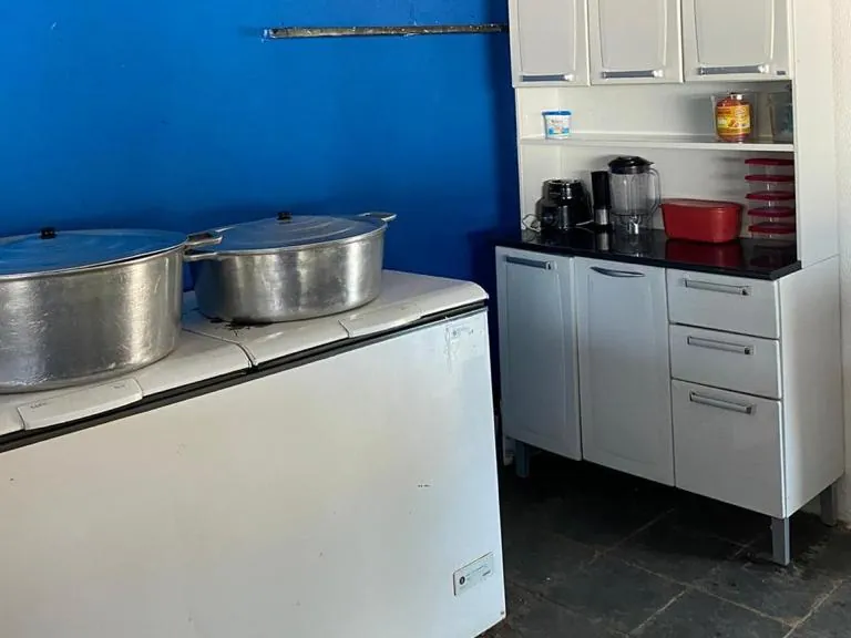 Cozinha com parede azul, freezer horizontal com duas panelas grandes e armário branco com liquidificador