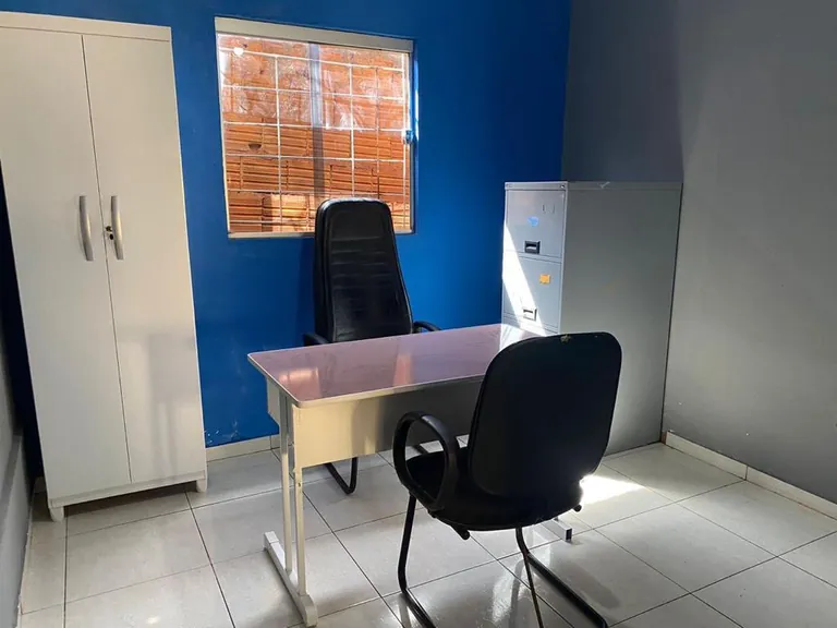 Sala com parede azul, mesa de escritório, duas cadeiras pretas, armário e arquivo de aço